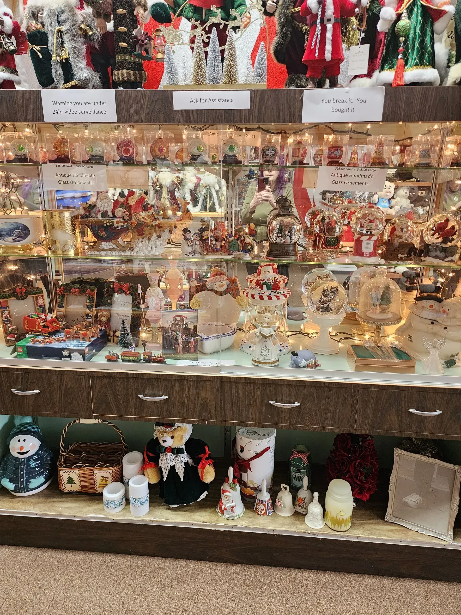 A display cabinet filled with Christmas decorations, including Santa figures, ornaments, and seasonal items.