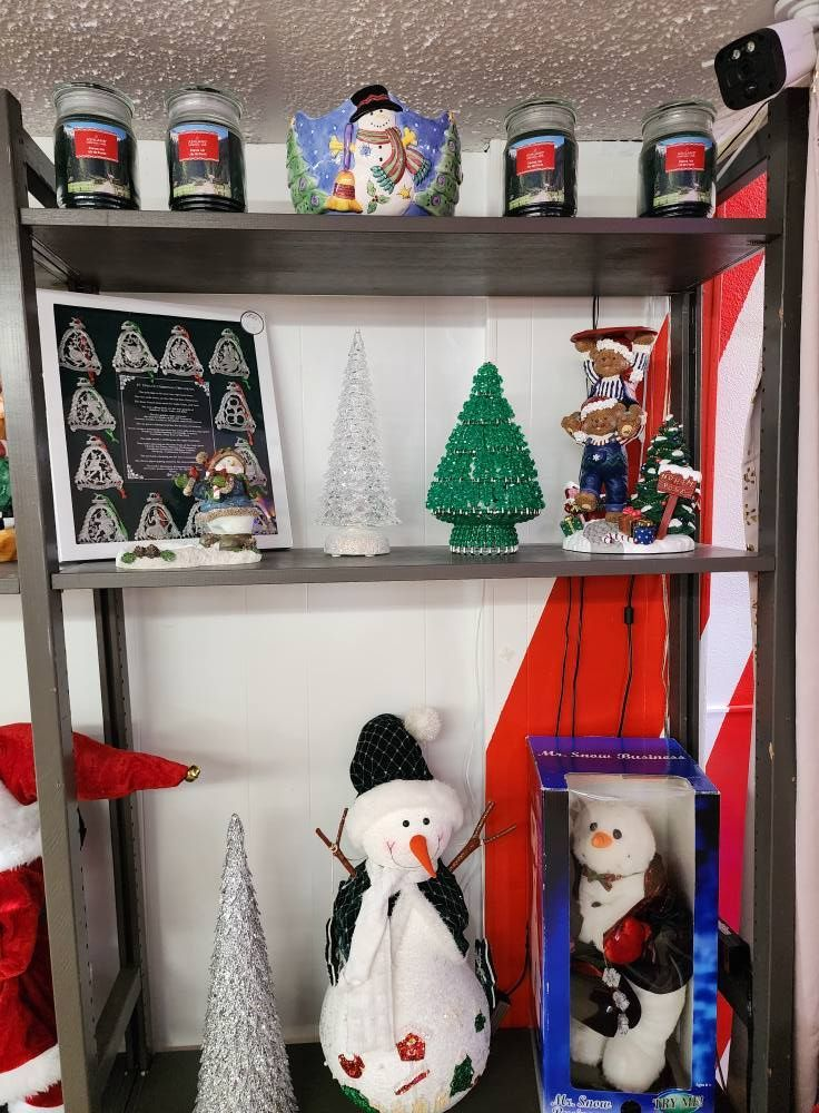 Shelf decorated with Christmas items including snowmen, candles, and trees.