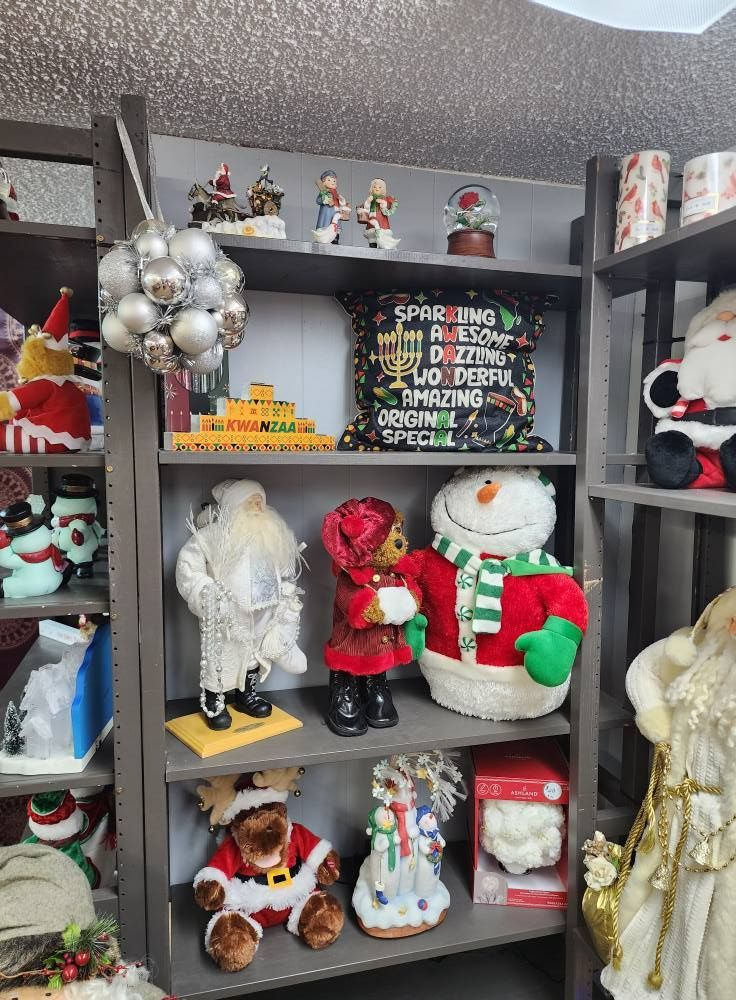 Shelves displaying Christmas decorations: plush snowmen, Santas, ornaments, figurines, and a festive pillow.
