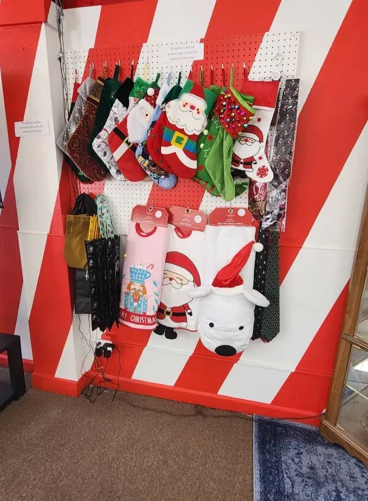 Christmas stockings and gift bags on a red and white striped wall, displayed in a store.