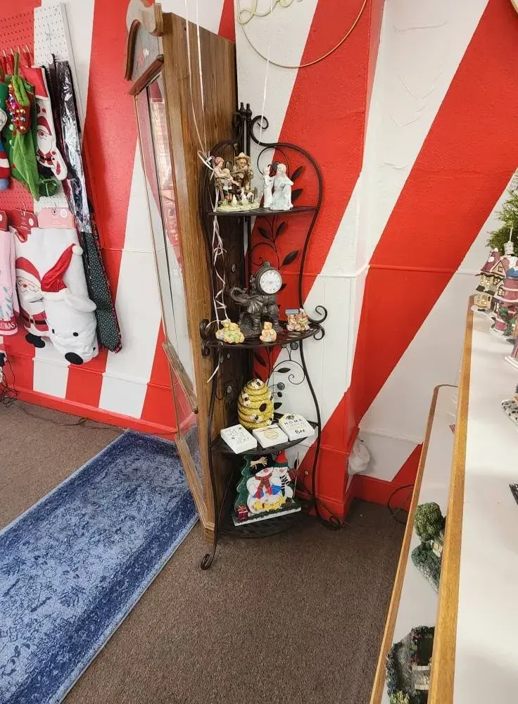 Shelf with figurines against red and white striped wall; blue rug in foreground.