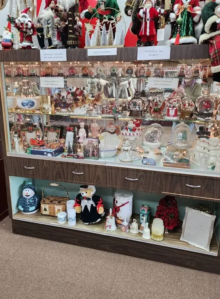 Display case filled with various holiday figurines and decorations, mostly Santa themed.