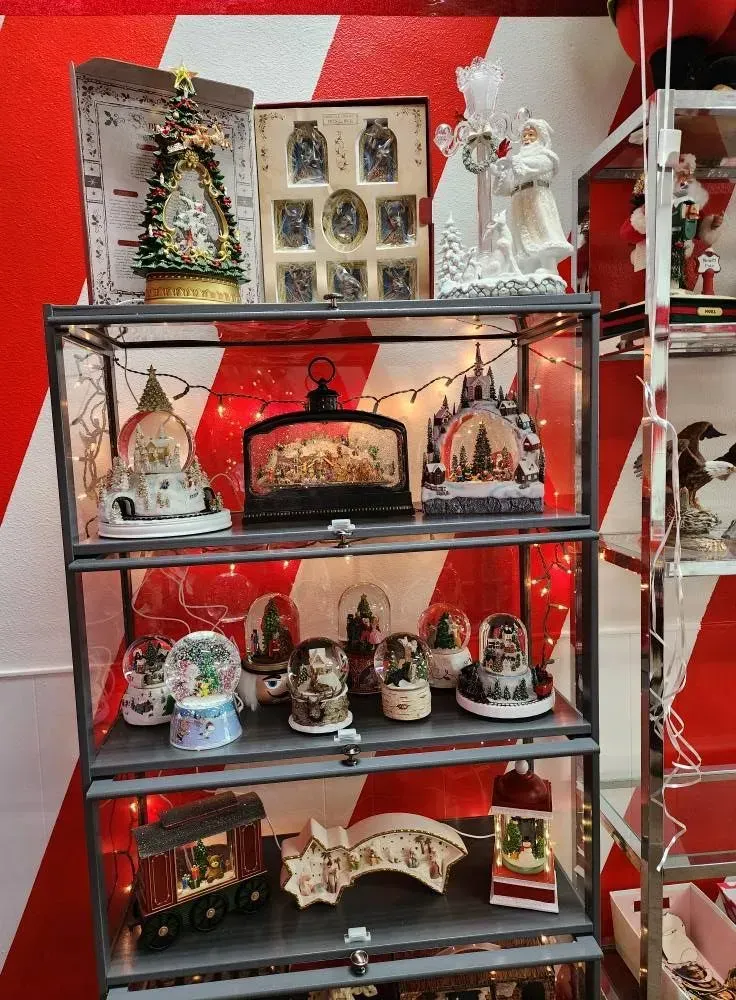Christmas decorations displayed on shelves in front of red and white striped wall.