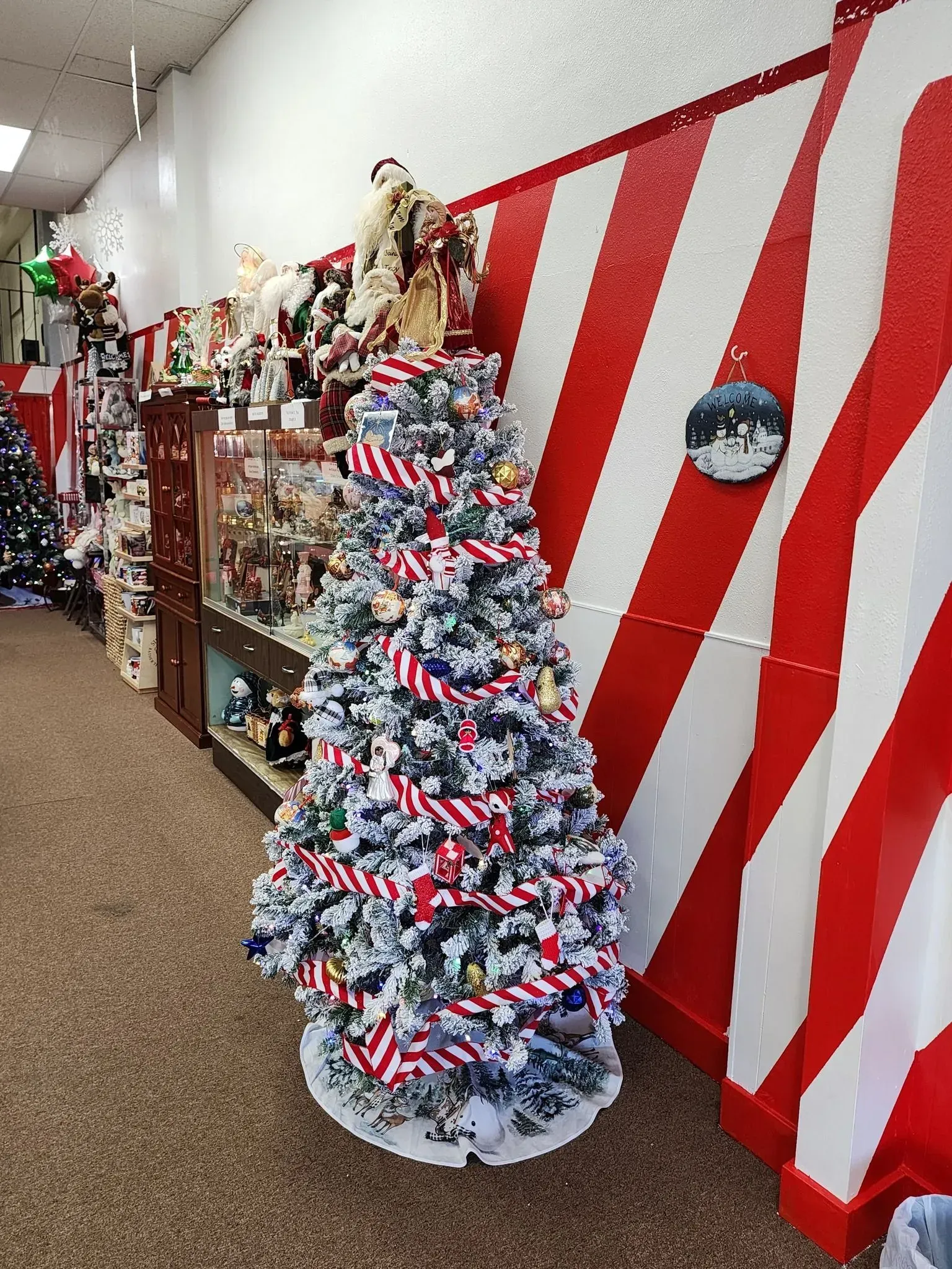 Christmas tree decorated with American flags in a store with red and white striped wall.