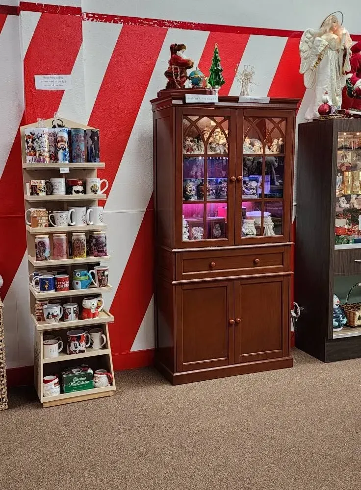 Wooden shelves display mugs. A cabinet holds items, next to another cabinet. Red and white striped wall.