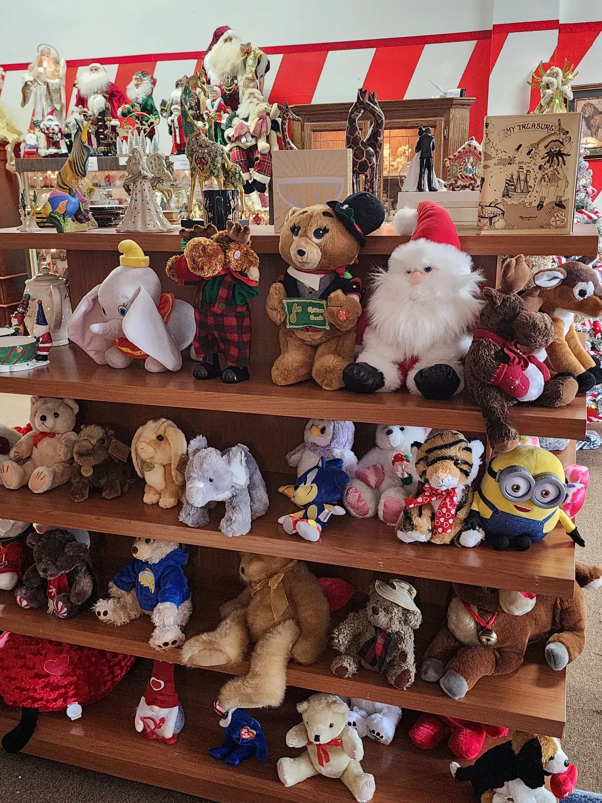 Shelves filled with various plush toys, including teddy bears, Santas, and Minions, displayed in a store.