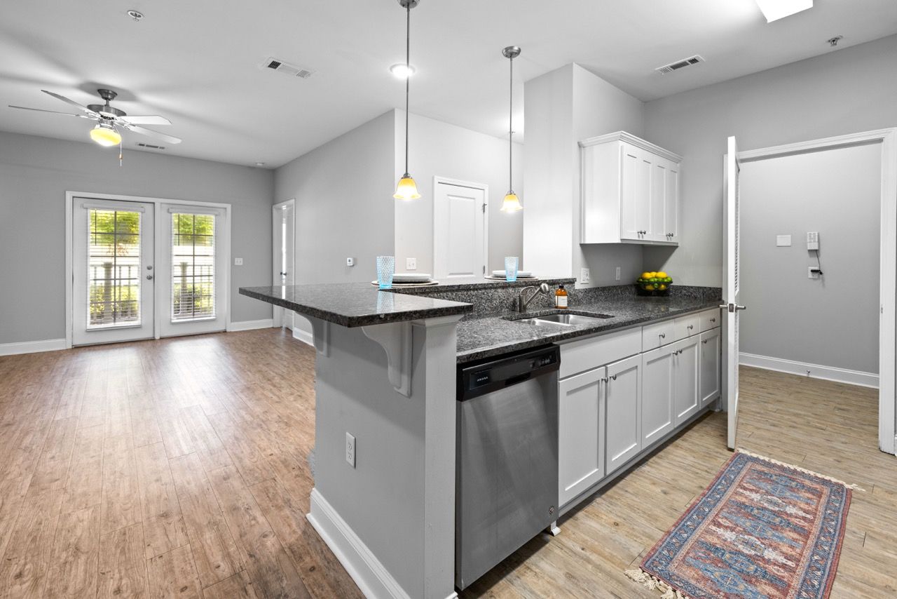 Open-concept kitchen with granite countertops, an island, and a stainless steel dishwasher.