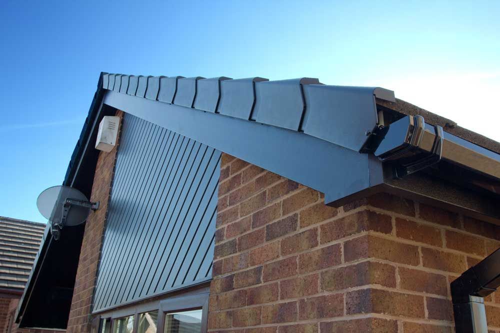 Brick building with black siding and roofline, clear blue sky.