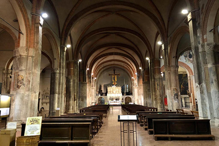 Interno di una chiesa con soffitto a volta, file di banchi e altare in lontananza.
