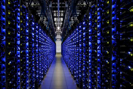 File di server in un data center, illuminati da luci blu, che creano un lungo corridoio.