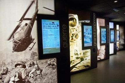 Mostra museale con pannelli che illustrano la guerra, un astronauta ed eventi storici.