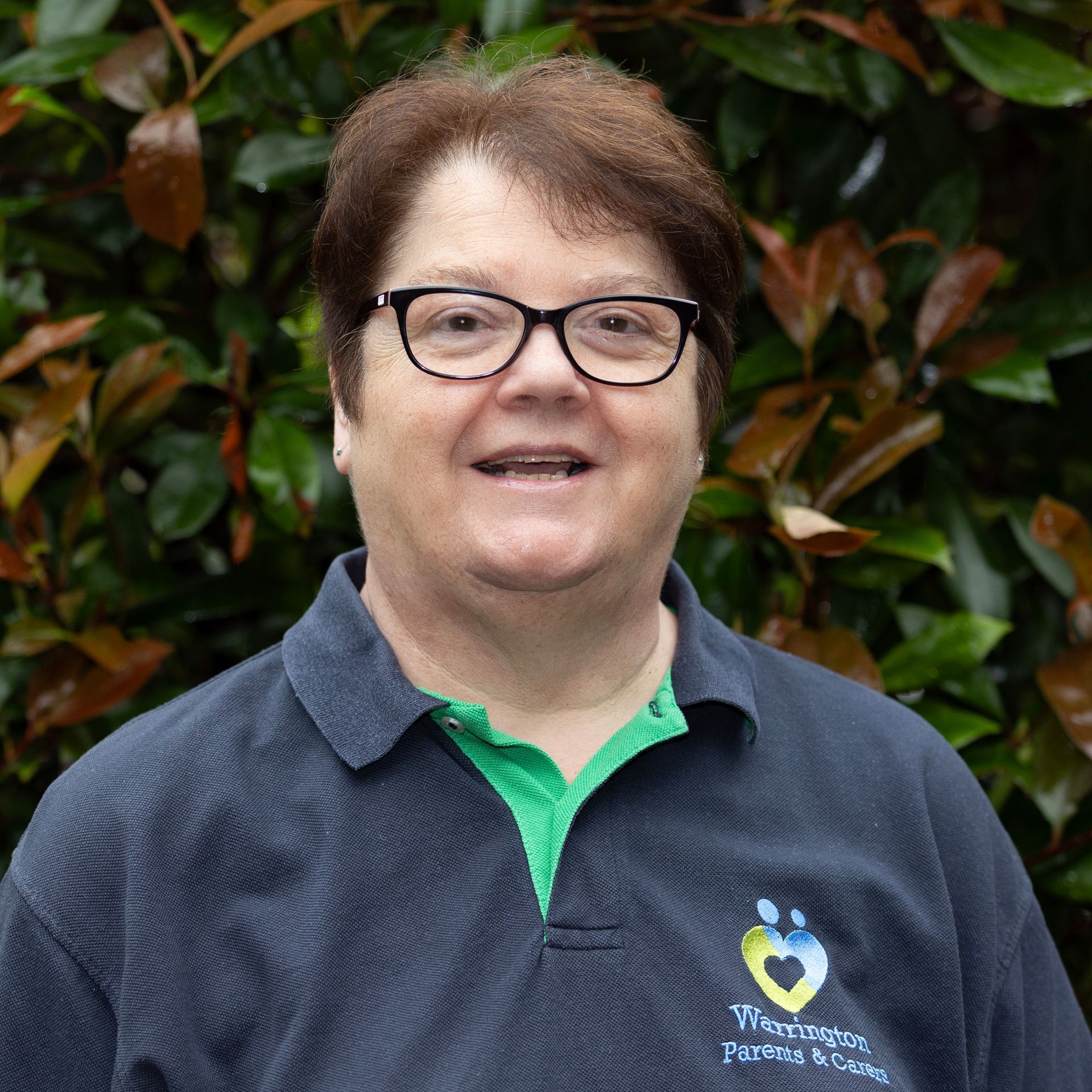 A woman wearing glasses and a blue shirt is smiling for the camera.