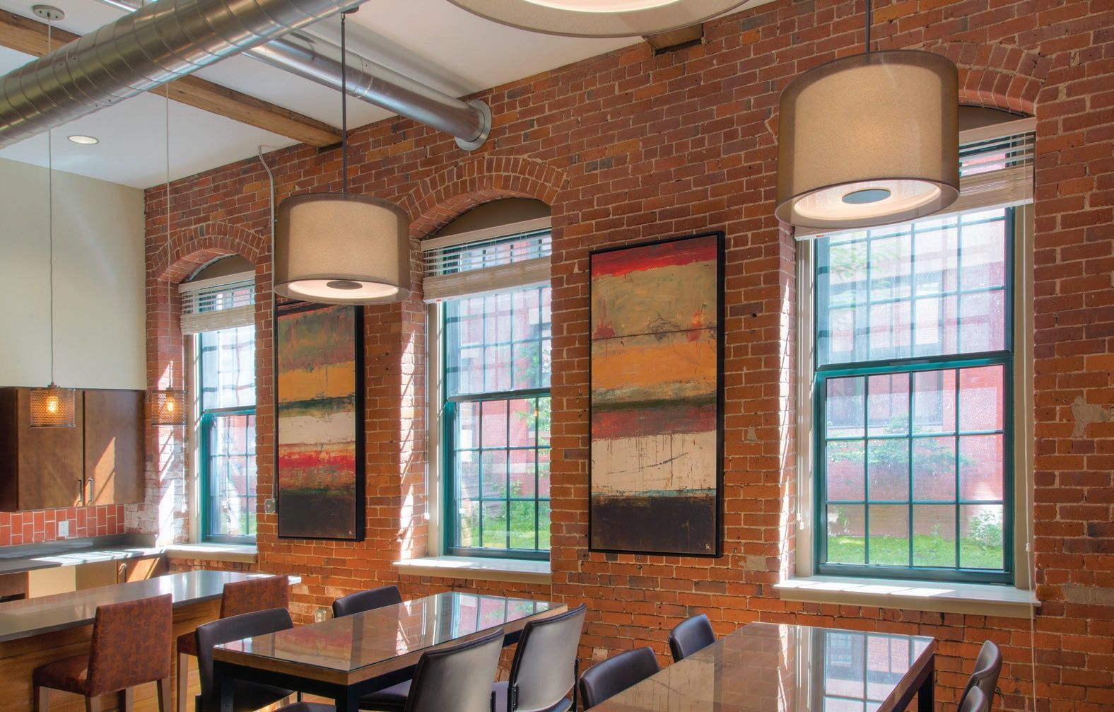Brick-walled restaurant with large windows, pendant lights, and wooden tables and chairs