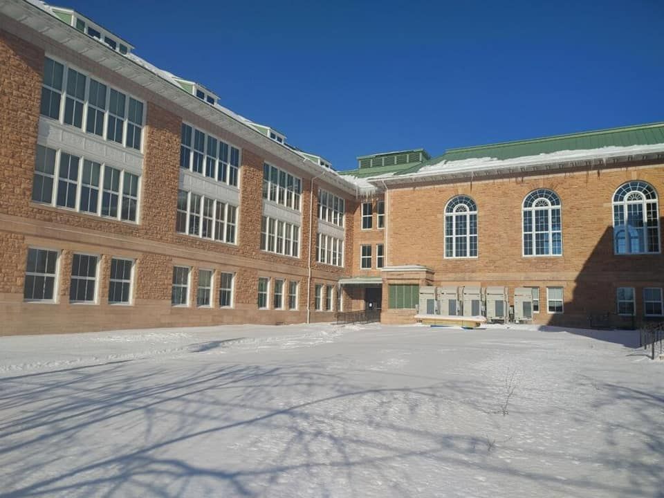 Brick school courtyard covered in snow, with large windows under a bright blue sky