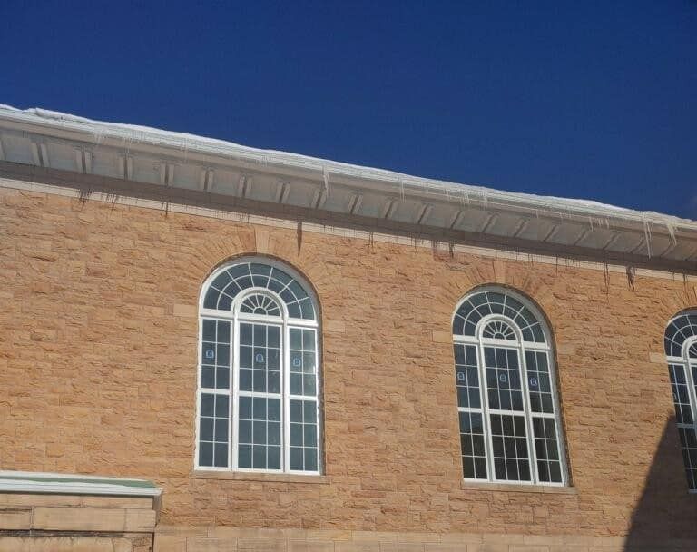 Brick building facade with two arched white-trimmed windows under a blue sky