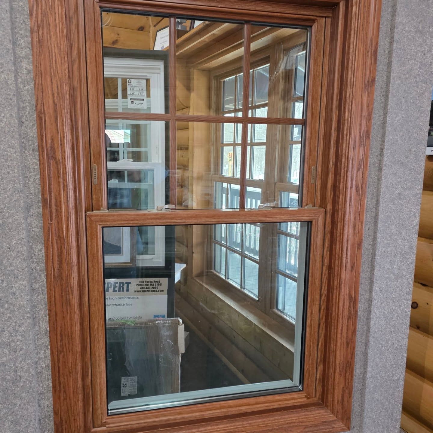 Wood-framed window looking into a narrow interior hallway with glass-paneled doors and a box inside.