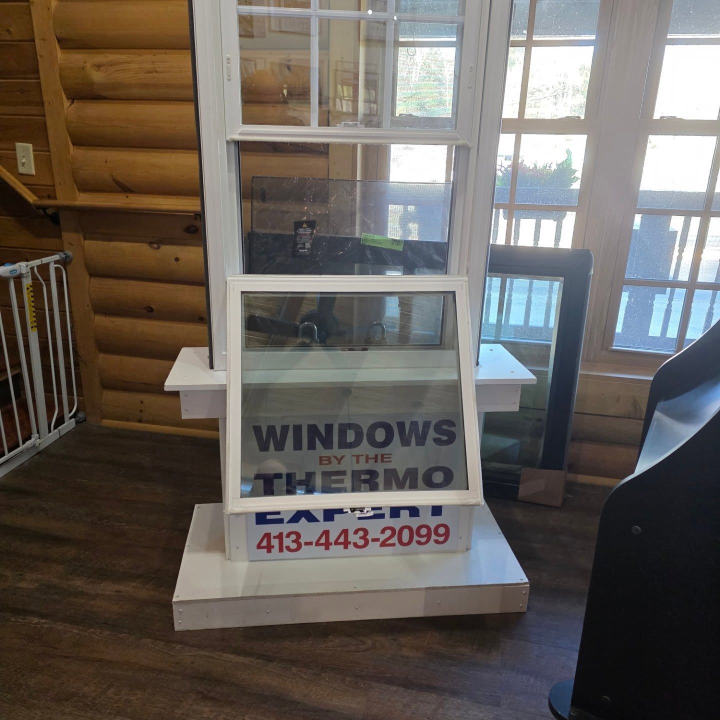 Window display with a white-framed flyer advertising “Windows by Thermo” and phone number 413-443-2099.