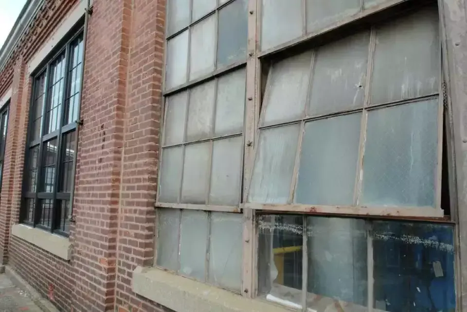 Old brick building with large, weathered multi-pane windows.