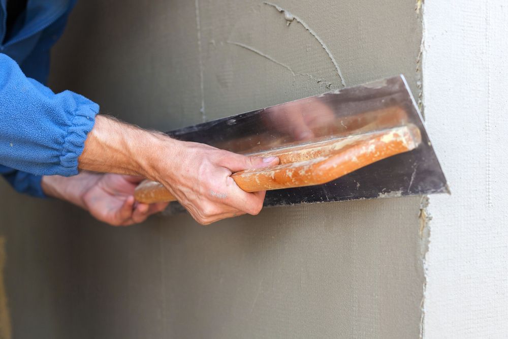A Man is Plastering a Wall With a Trowel — Barrington Coast Contracting in Bulahdelah, NSW