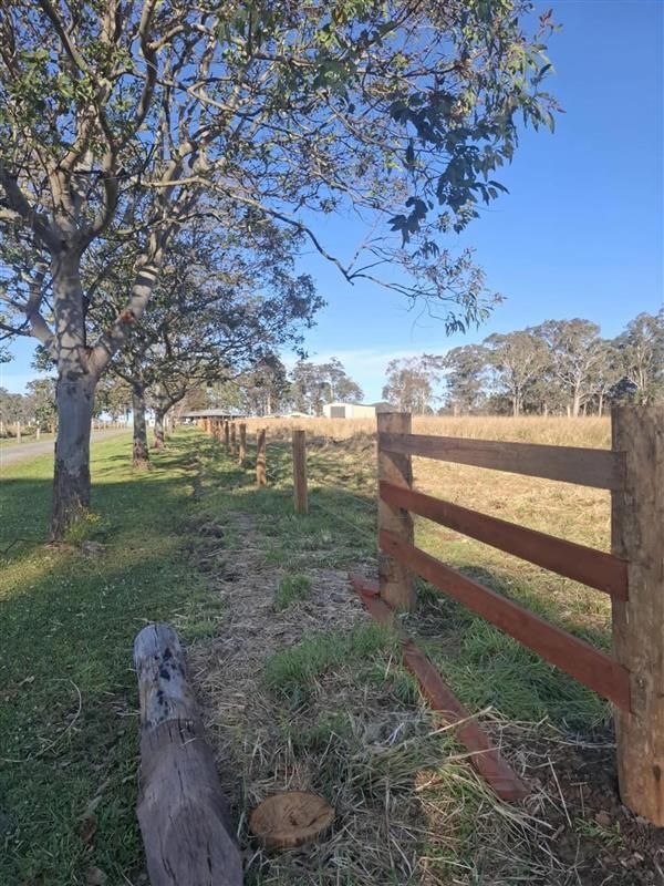 A Long Green Fence is Surrounded by Grass and Trees — Barrington Coast Contracting in Bulahdelah, NSW