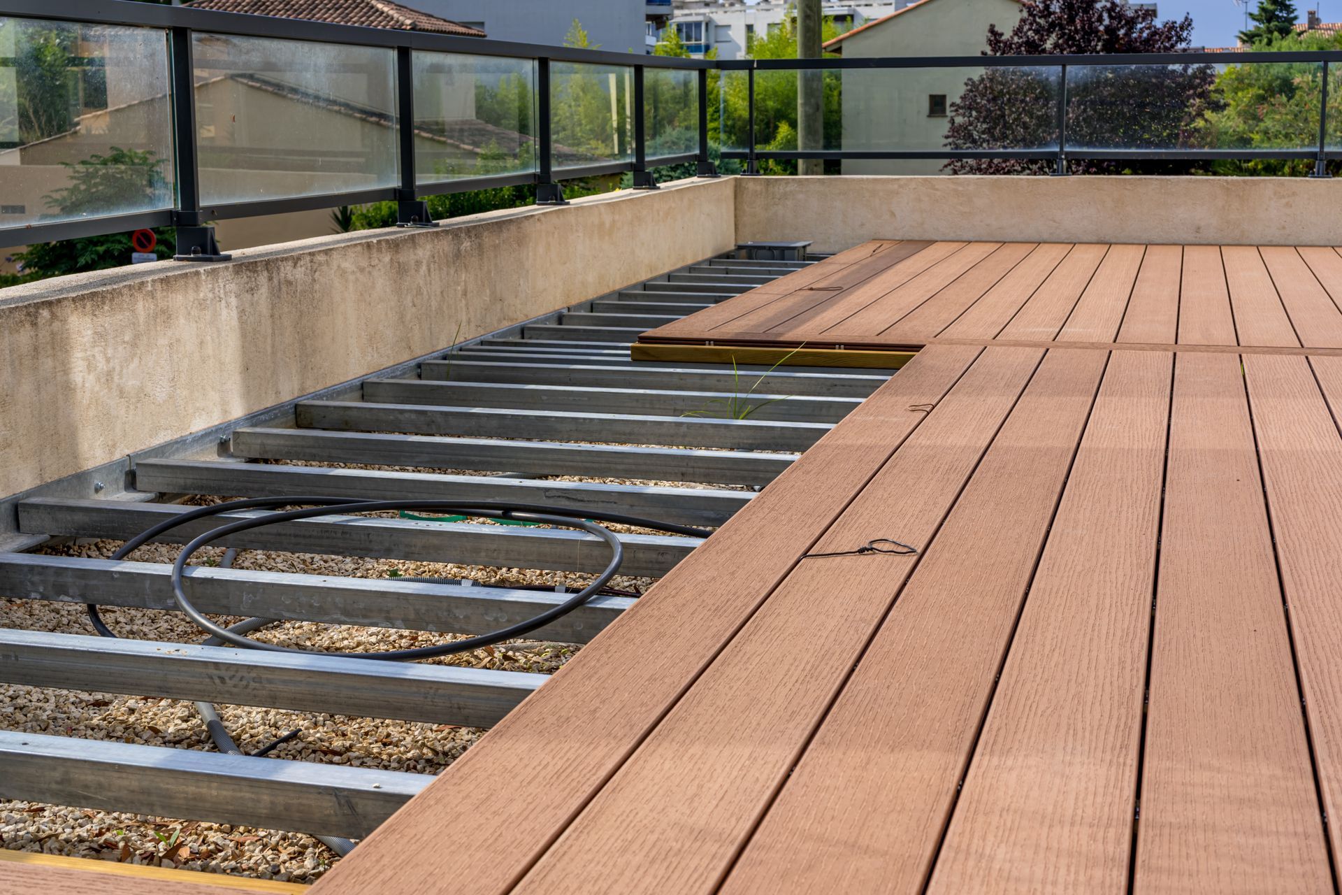 Partially constructed outdoor deck with brown planks and grey support beams.