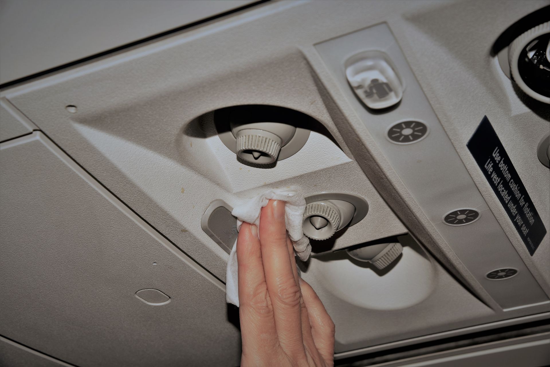 Hand wiping a car’s overhead console and dome light with a cloth Hand wiping a car’s overhead console and dome light with a cloth