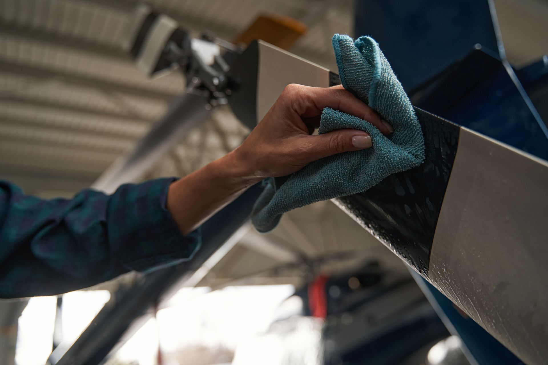 Hand wiping a metal surface with a blue cloth in a workshop
