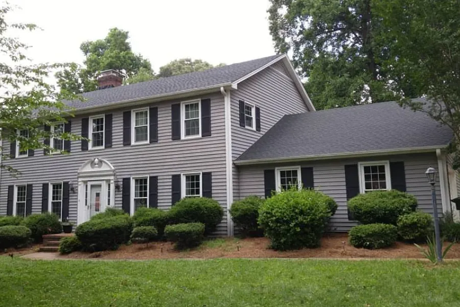 A large grey house with black shutters on the windows