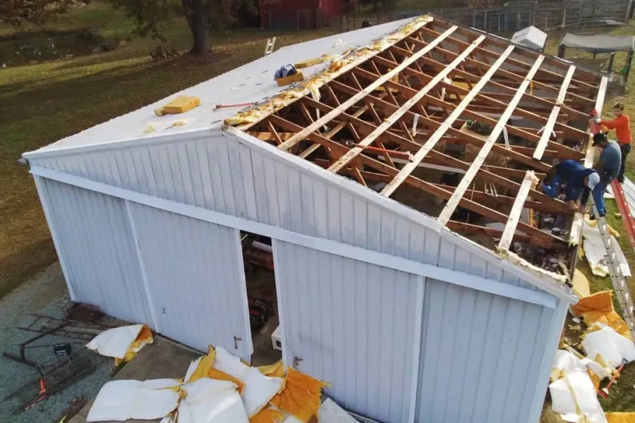 A white building with a roof that has been damaged by a tornado.