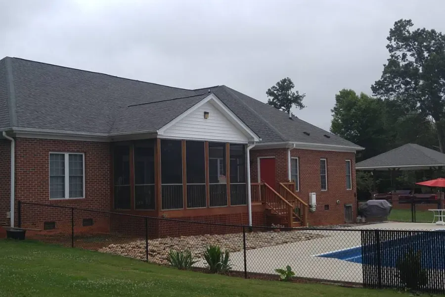 A brick house with a screened in porch and a pool