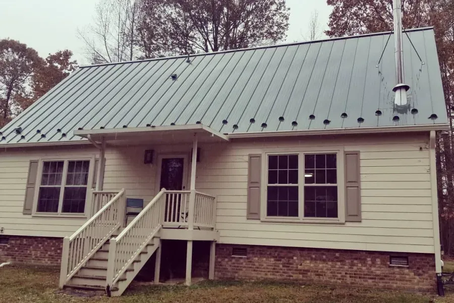 A white house with a metal roof and stairs