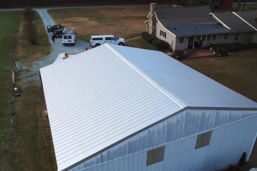 An aerial view of a large white building with a white van parked in front of it.