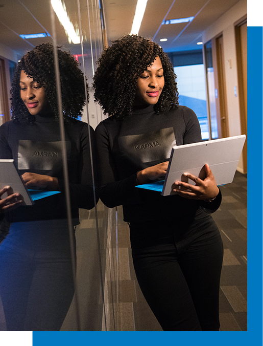 A woman is standing in front of a mirror holding a tablet computer.
