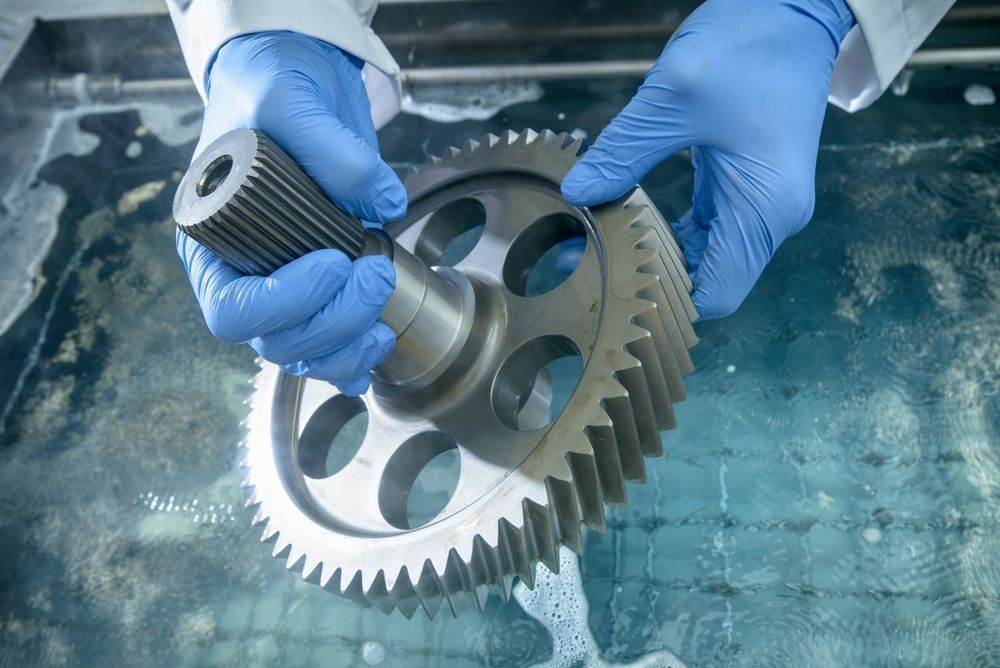 A Person Wearing Blue Gloves Is Holding A Gear In Their Hands — D.E.M Solutions Pty Ltd In Caboolture, QLD