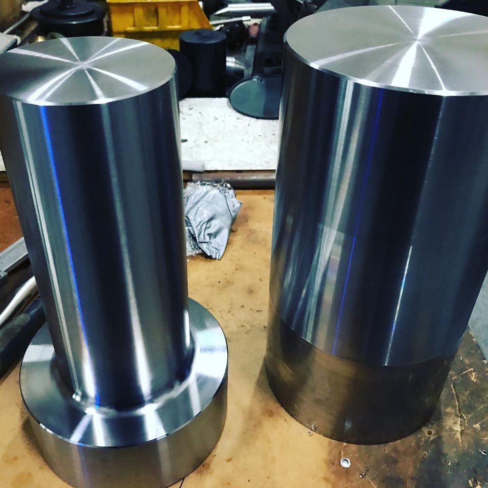 Two Metal Cylinders Are Sitting On A Wooden Table — D.E.M Solutions Pty Ltd In Caboolture, QLD