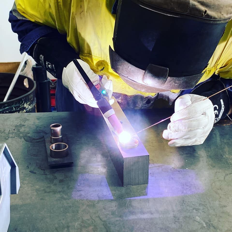 A Man Wearing A Welding Helmet Is Welding A Piece Of Metal — D.E.M Solutions Pty Ltd In Caboolture, QLD