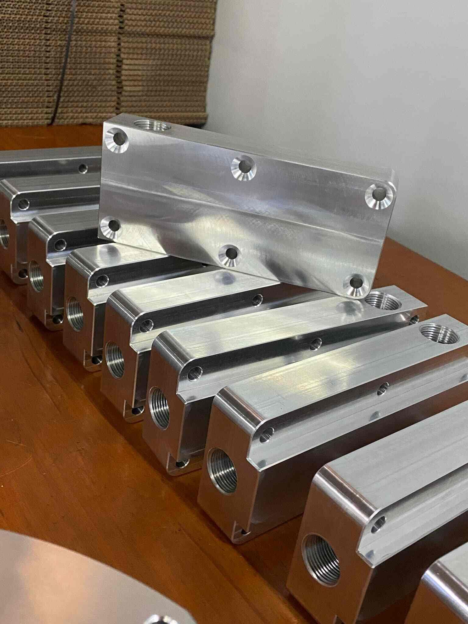 A Bunch Of Metal Pieces Are Sitting On Top Of A Wooden Table — D.E.M Solutions Pty Ltd In Caboolture, QLD