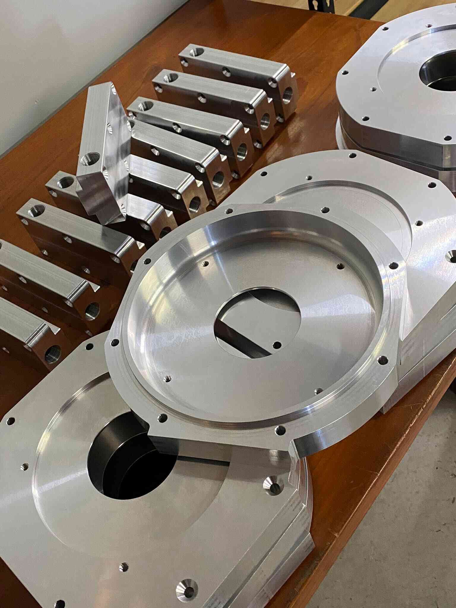 A Bunch Of Metal Parts Are Sitting On A Wooden Table — D.E.M Solutions Pty Ltd In Caboolture, QLD