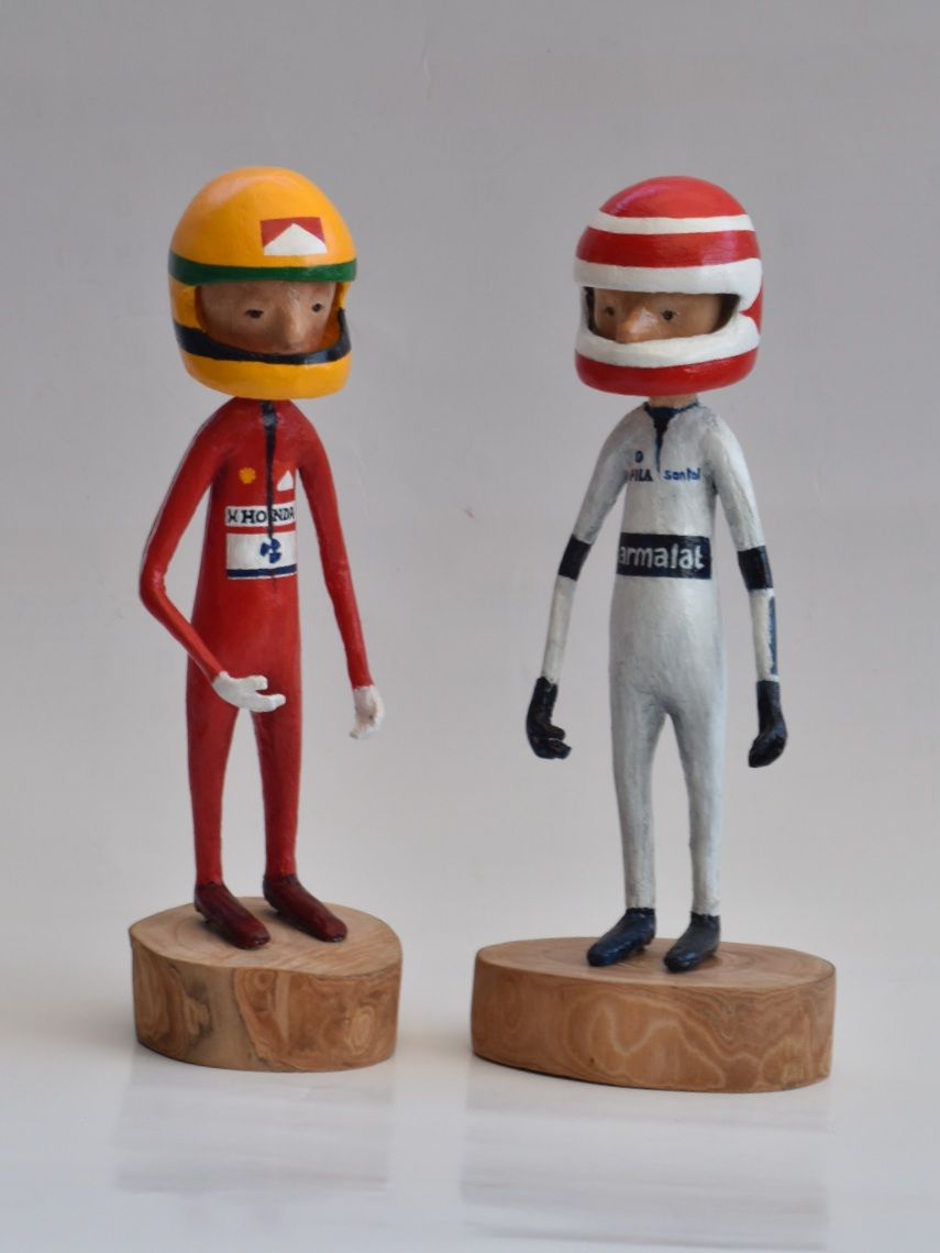Twee beeldjes staan ​​naast elkaar, waarvan er één een helm draagt ​​met de tekst marlboro, senna en piquet