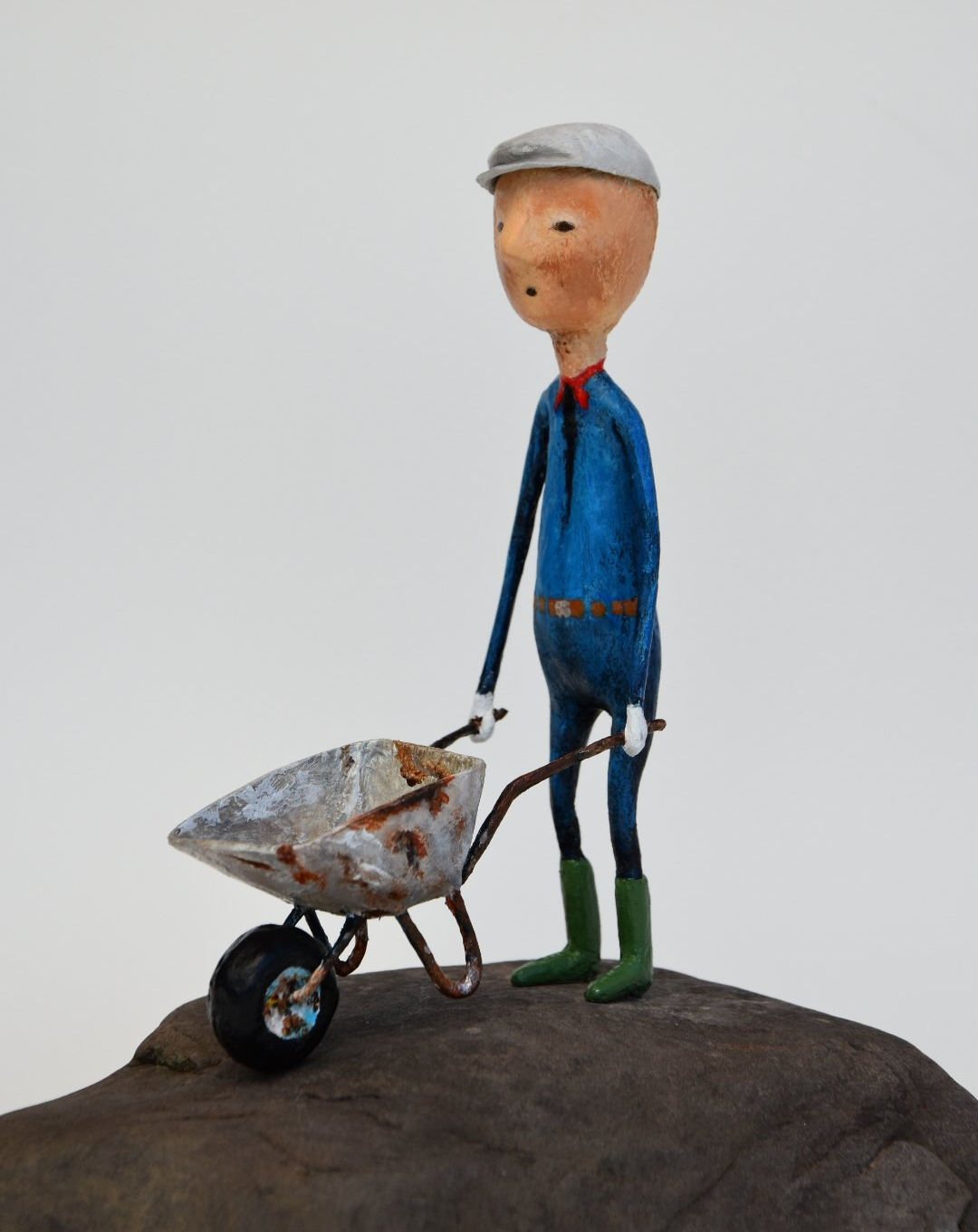 Een tekenfilmfiguur duwt een kruiwagen op een rots
