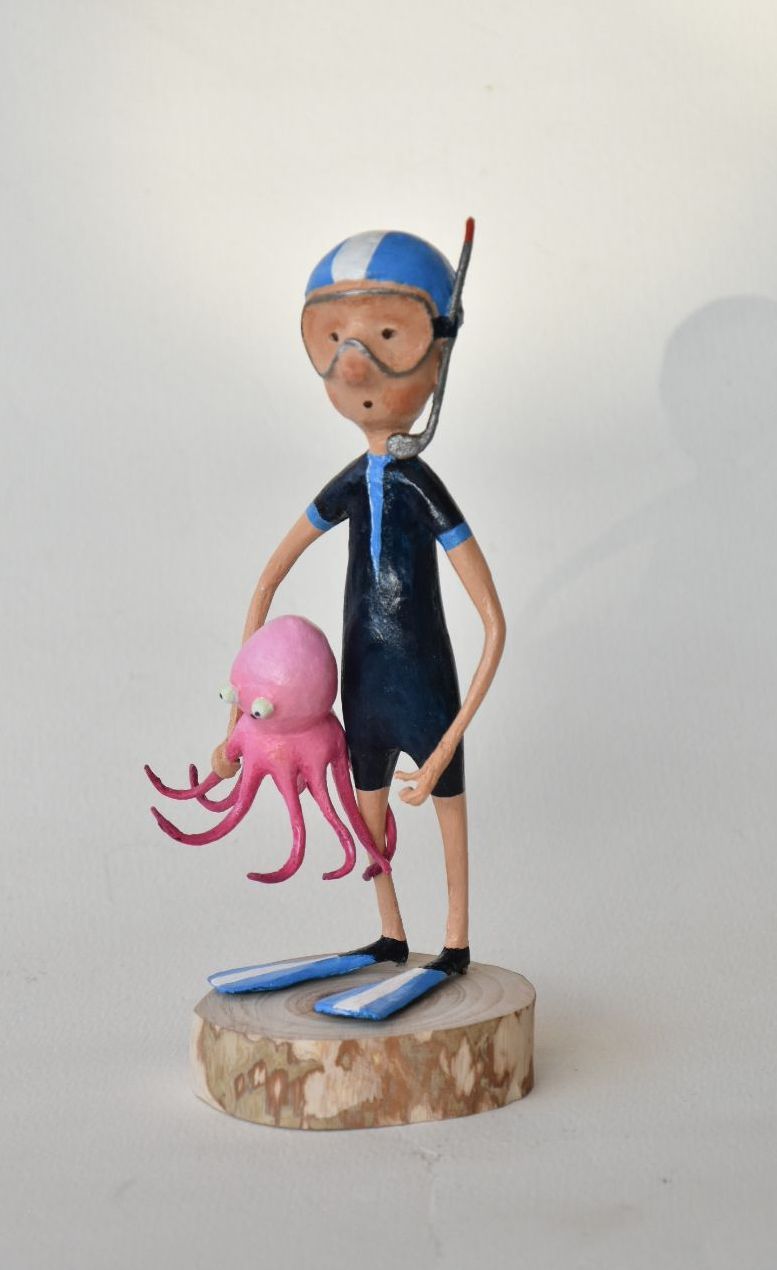 Een standbeeld van een man in een wetsuit die een octopus vasthoudt