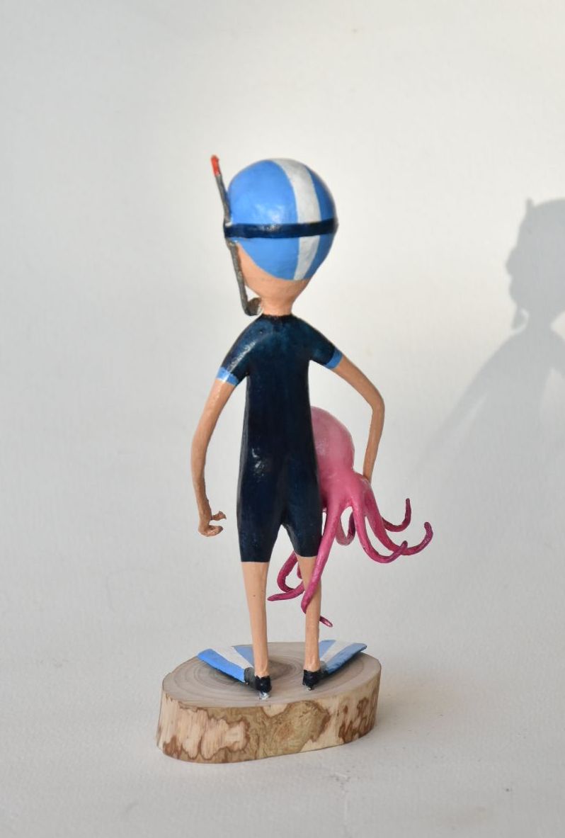 Een standbeeld van een jongen in een wetsuit die een octopus vasthoudt