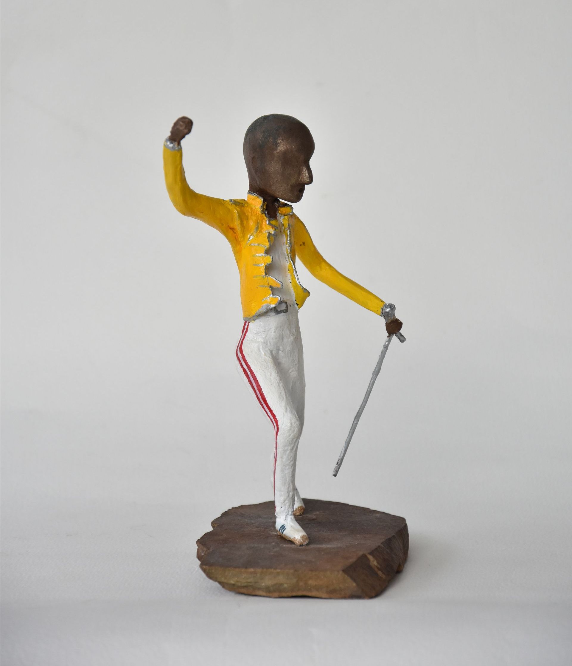Een standbeeld van een man in een geel jasje met een wandelstok