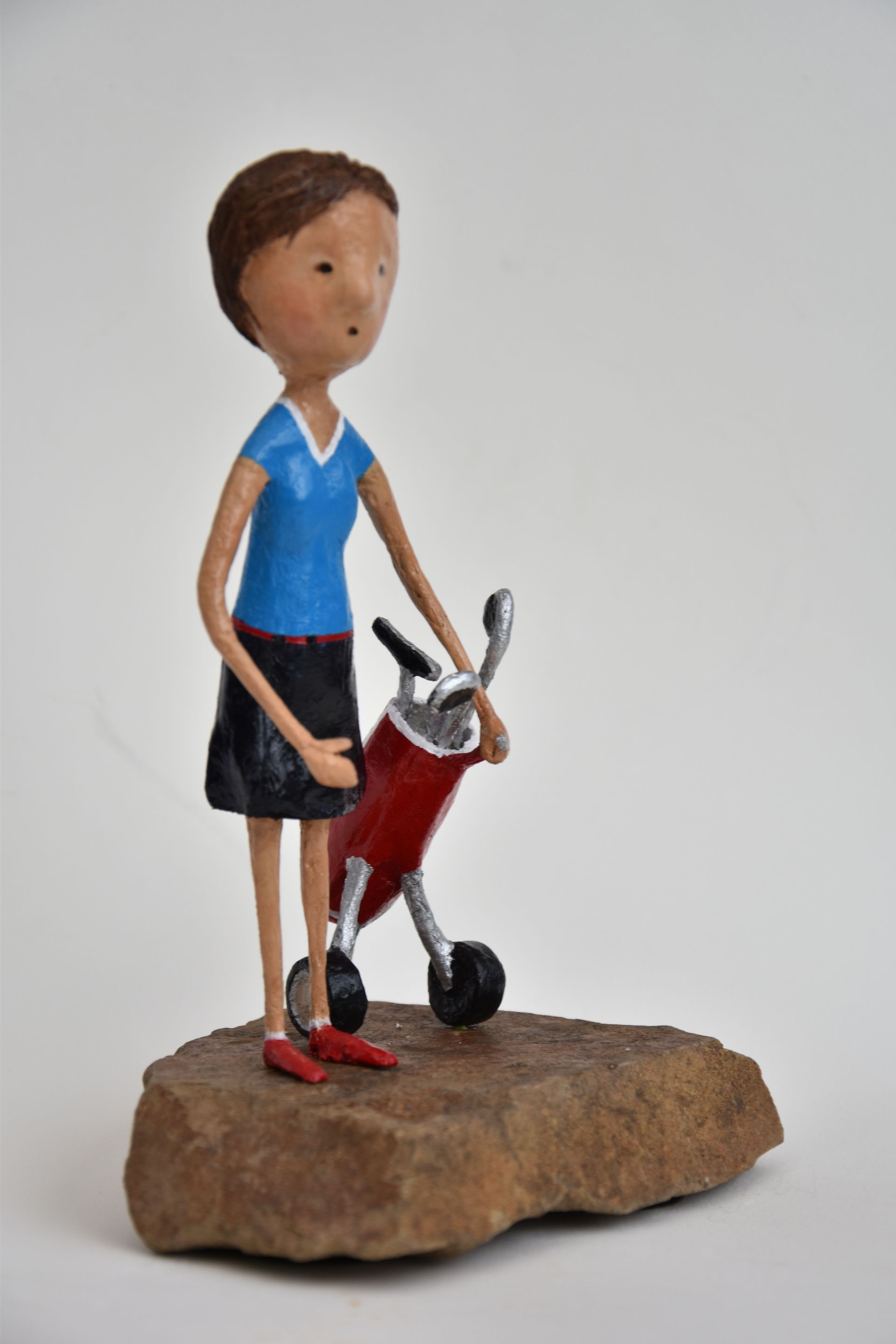 Een standbeeld van een vrouw die naast een rode scooter staat