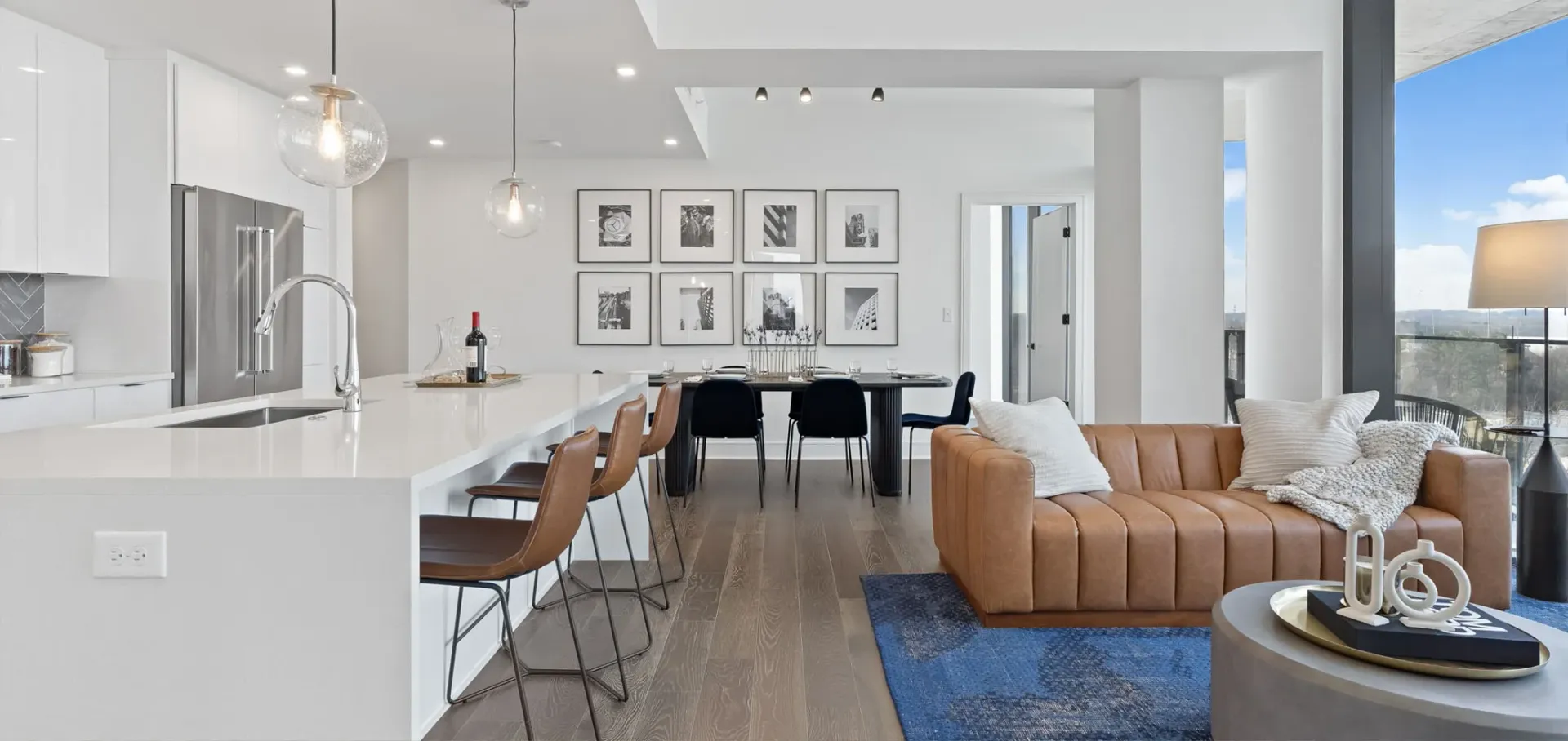 Modern apartment living room and kitchen with a sofa, dining table, and island.