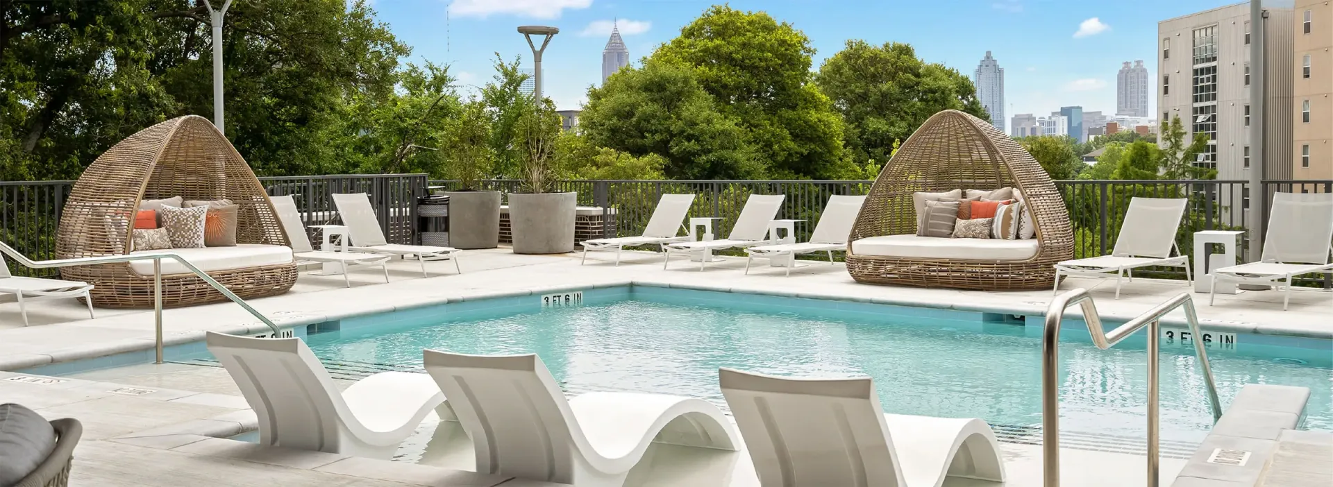 Outdoor swimming pool with lounge chairs and cabanas overlooking the city skyline.