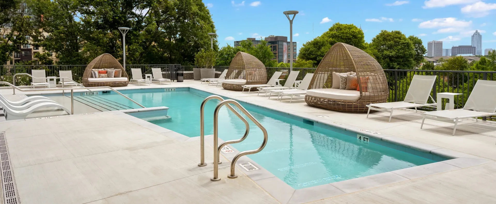 Luxury swimming pool with lounge chairs and cabanas overlooking the city skyline.