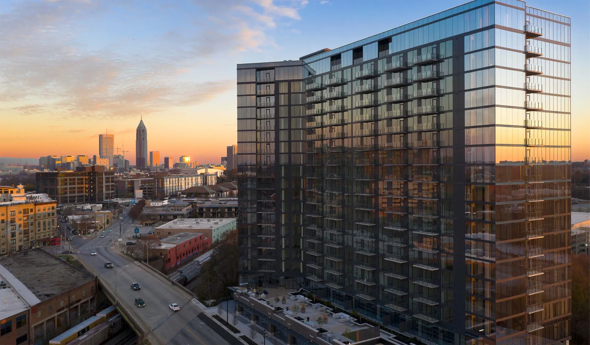 Exterior of a modern glass apartment building in a city skyline at sunset.