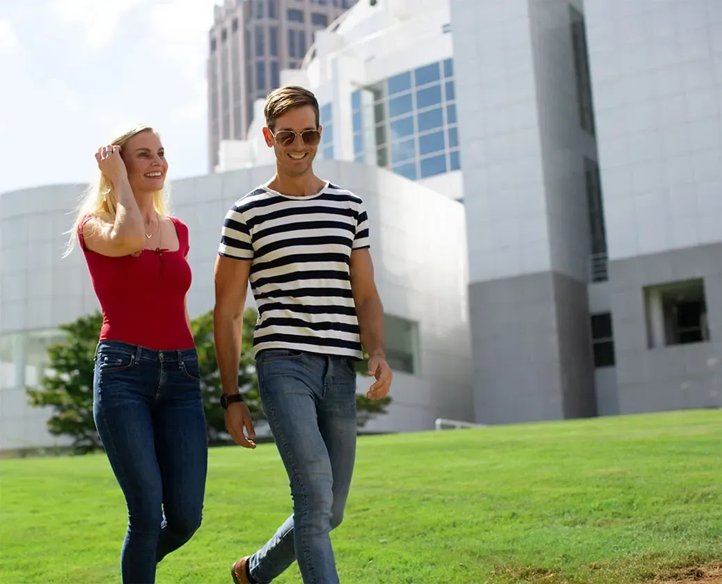 Couple walking and smiling in front of a modern building.