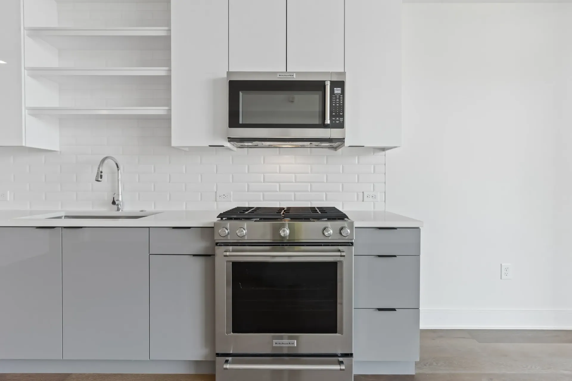 Modern kitchen with stainless steel appliances, white subway tile backsplash, and gray cabinetry.